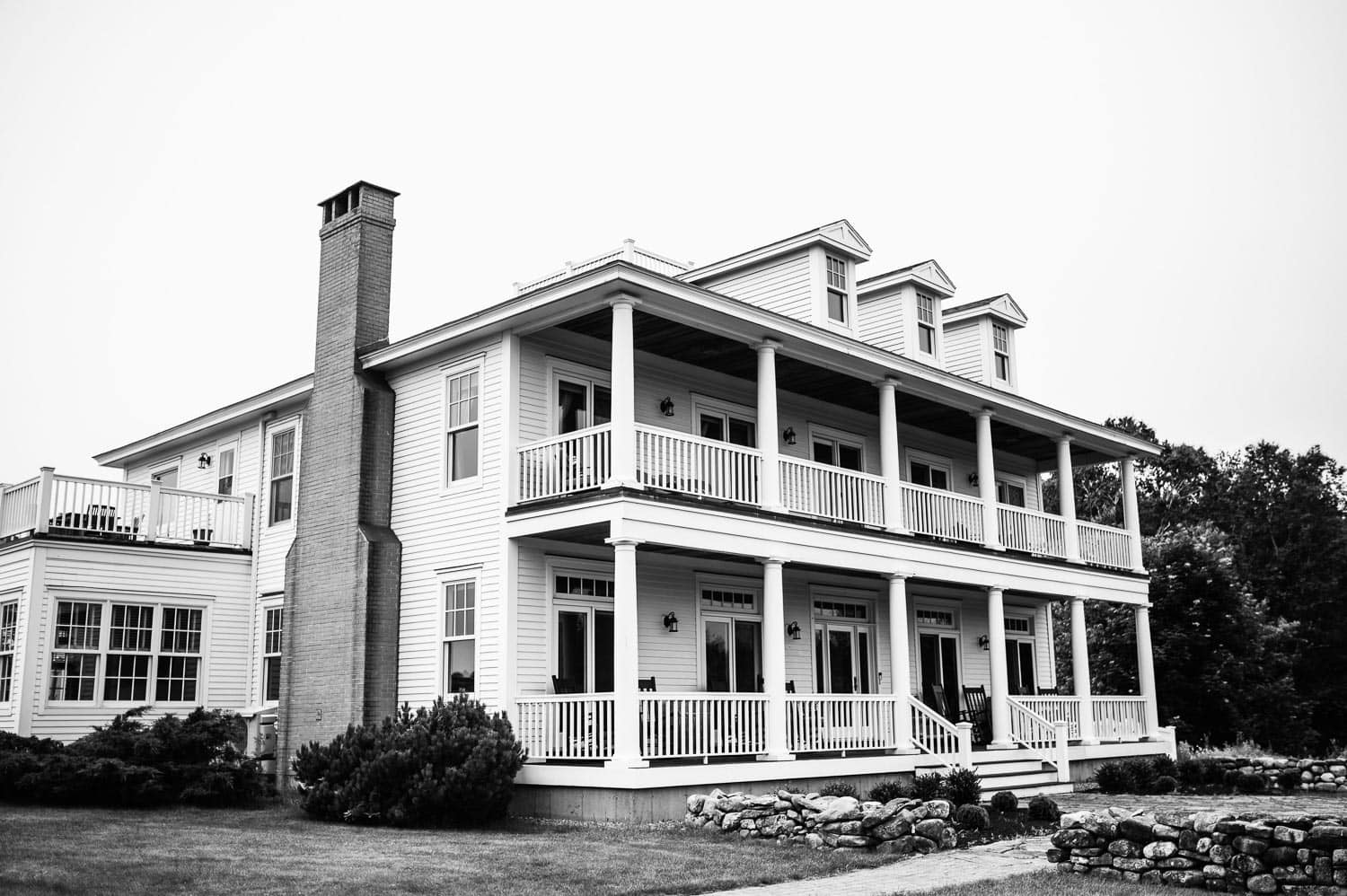 A white mansion with two front balconies and a chimney at Ash Point Estate.