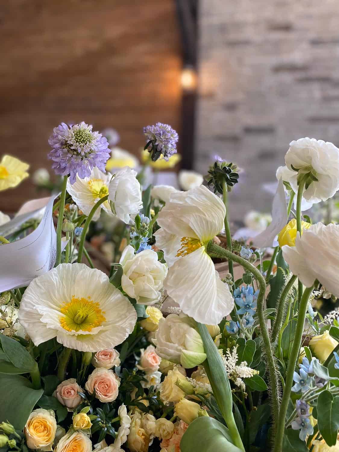 A floral arrangement featuring white poppies, pink roses, and purple blooms.