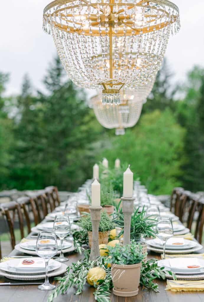 4 Steps To Plan A Luxury Wedding Weekend In Maine 1 Luxury wedding weekend in maine, elegant outdoor table with a crystal chandelier, adorned with candles, greenery, and set with fine dinnerware.