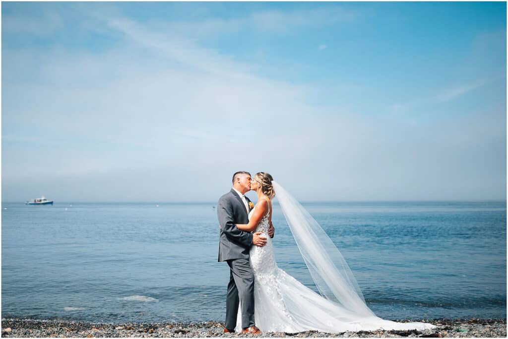Luxury venues in coastal maine, a bride and groom kissing in front of the water.