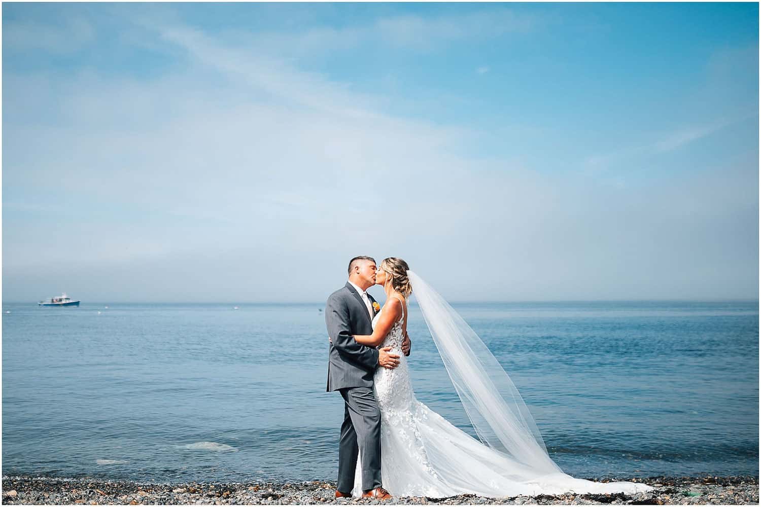 A bride and groom kissing in front of the water.