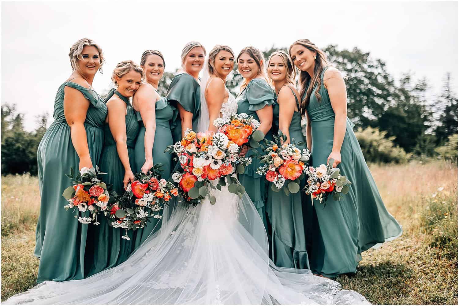 A bride and her bridesmaids standing in a field.