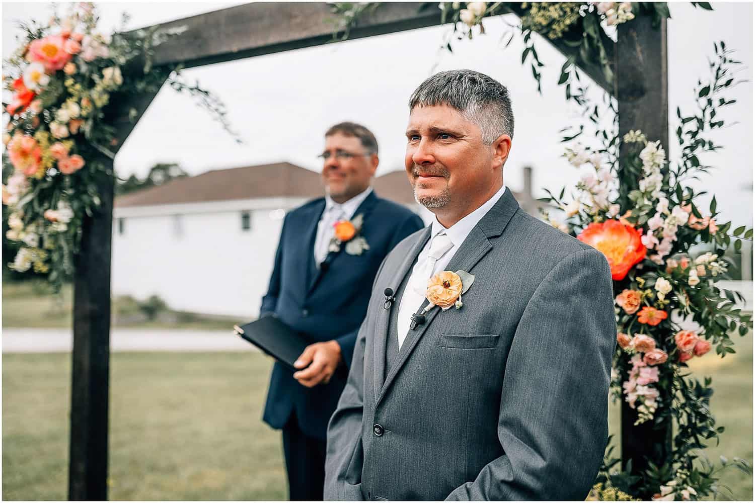 A groom smiling, waiting for his bride to walk down the aisle.