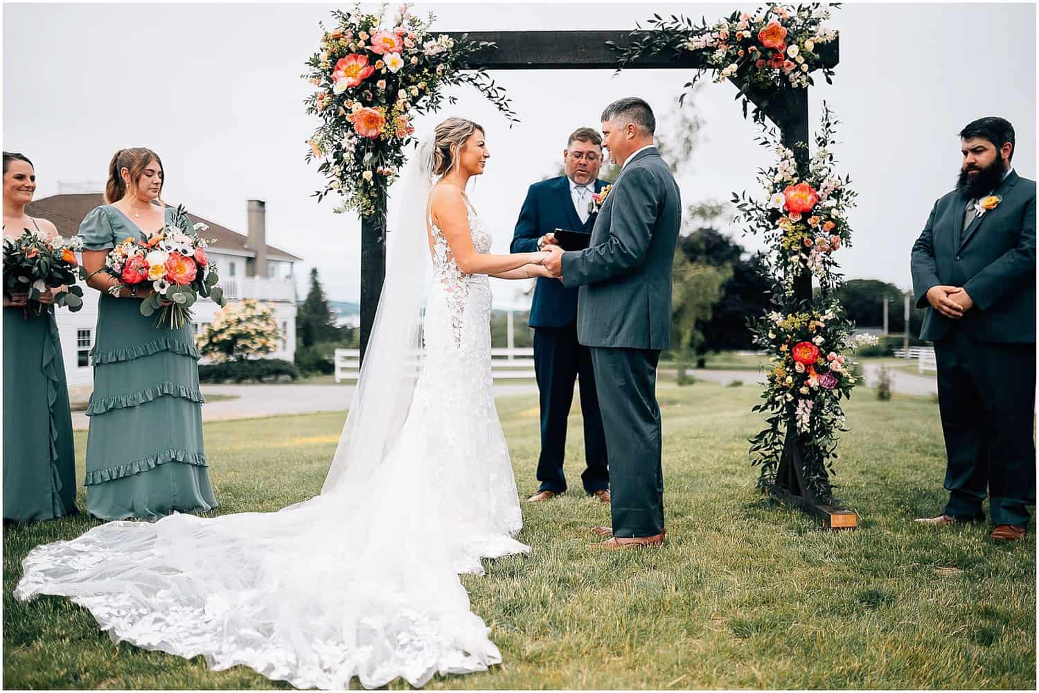 A bride and groom holding hands under a floral arch.