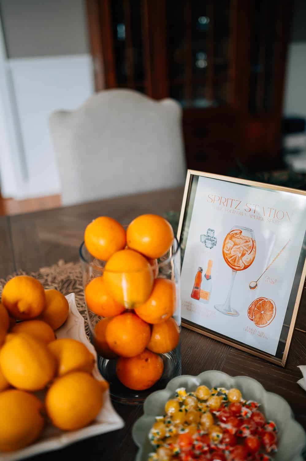 Luxury wedding weekend in maine, a display of fresh oranges next to a "spritz station" sign and a colorful salad on a table.