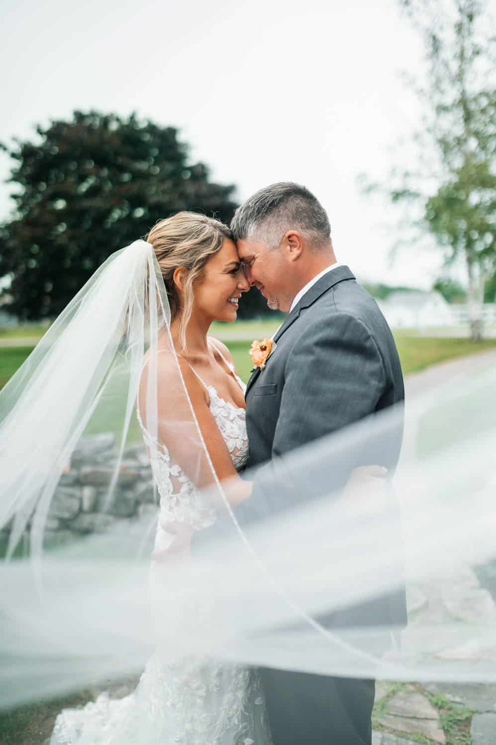 A man and woman in wedding attire, smiling and hugging.