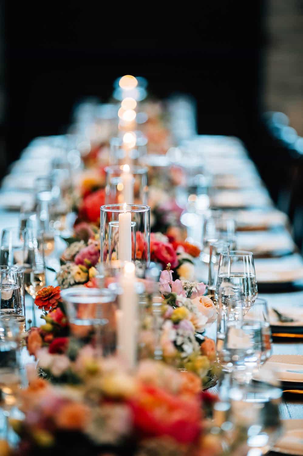 A long table with flowers and candles at a wedding reception.