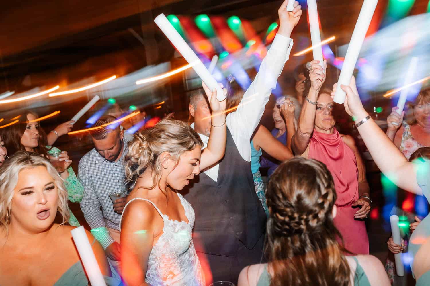 A bride and groom dancing at their reception with guests.