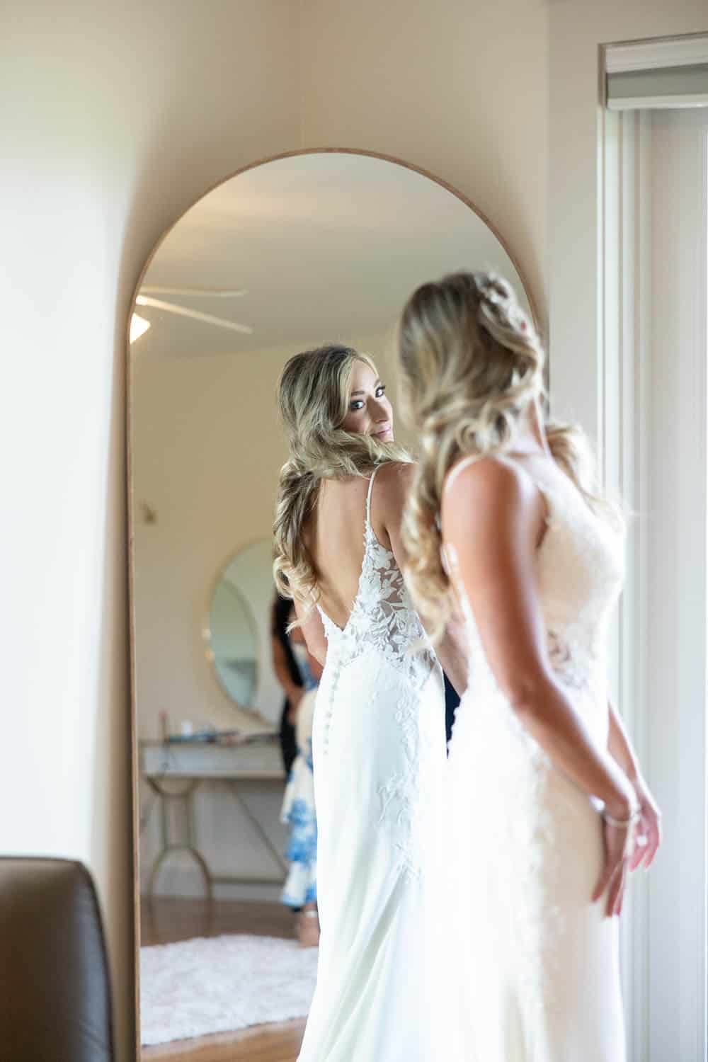 A bride looking over her shoulder into a mirror.