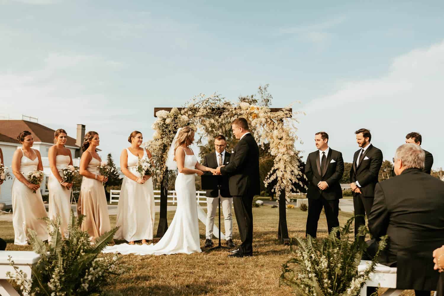 A bride and groom with their wedding party standing under a arch.