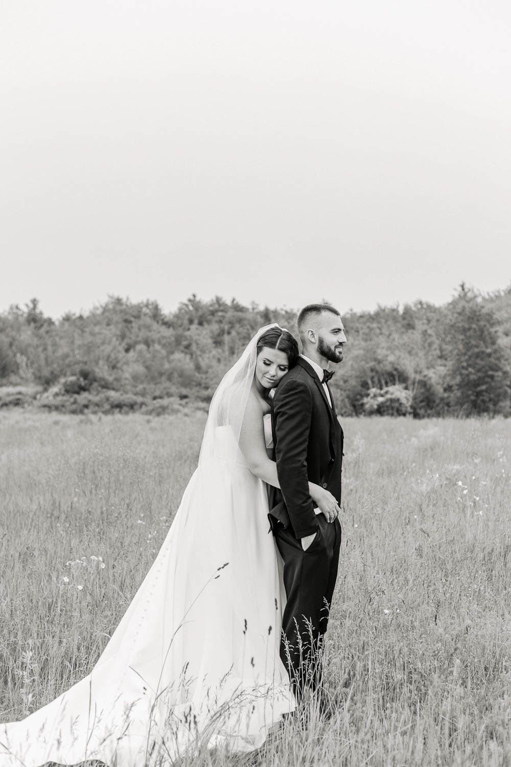 A bride and groom standing in a field.