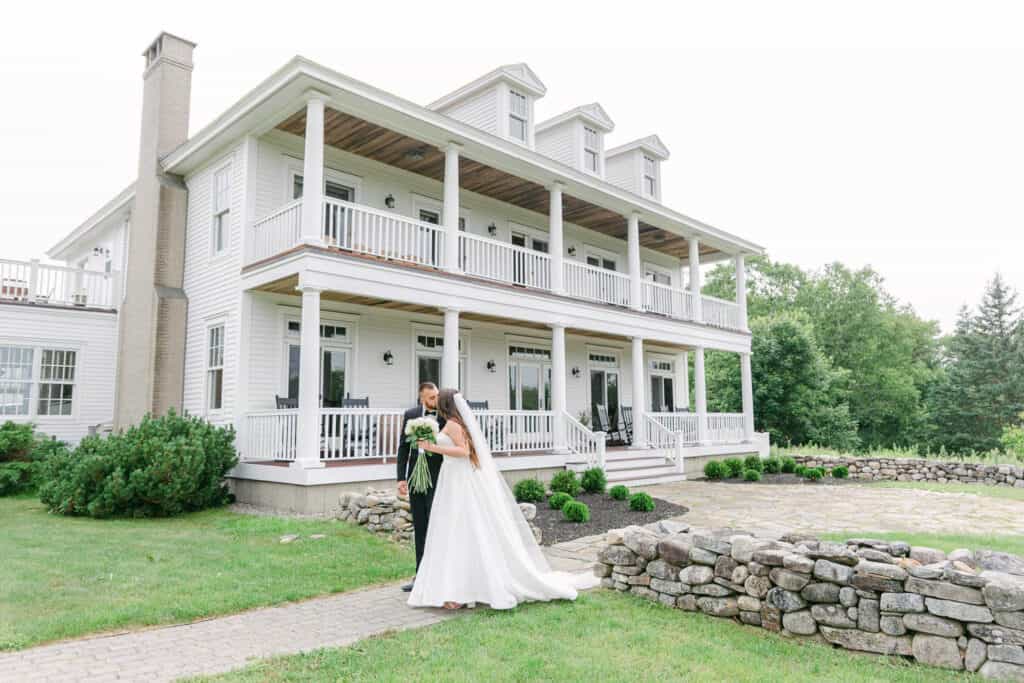 Luxury wedding weekend in maine, a bride and groom in front of a white mansion at ash point estate.