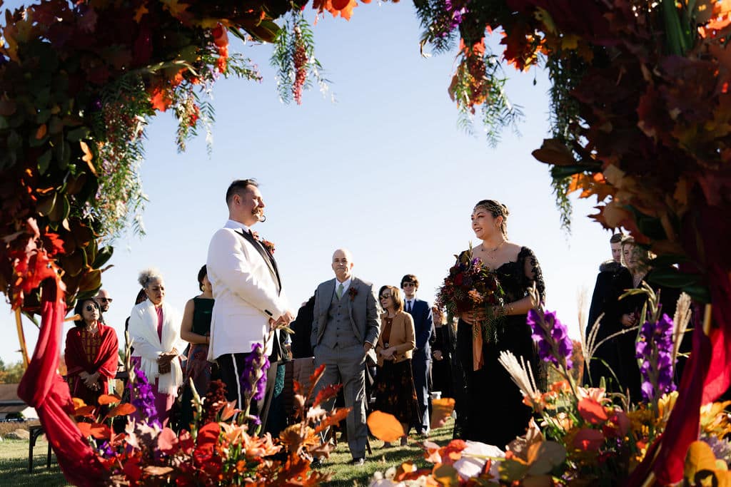 Best Maine Resorts For Weddings (Plus A Private Estate You Shouldn’t Miss) 4 Ash point estate maine resorts, couple exchanges vows in front of a large floral arrangement