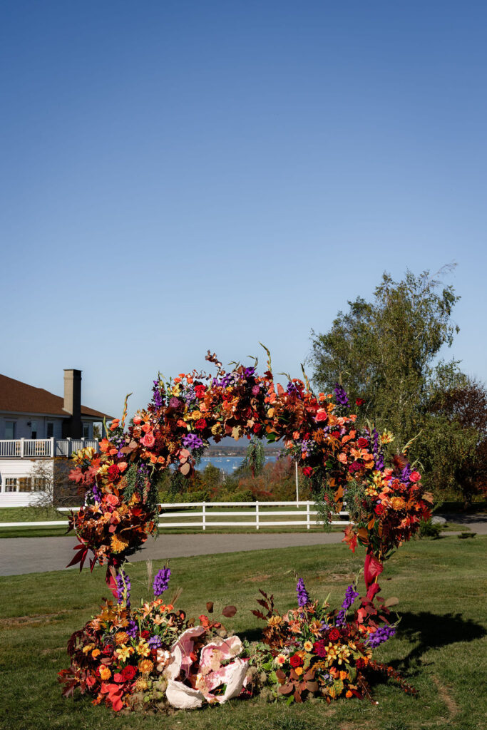 Ash point estate overlooking floral arch at wedding altar, ash point estate waterfront wedding venues in maine